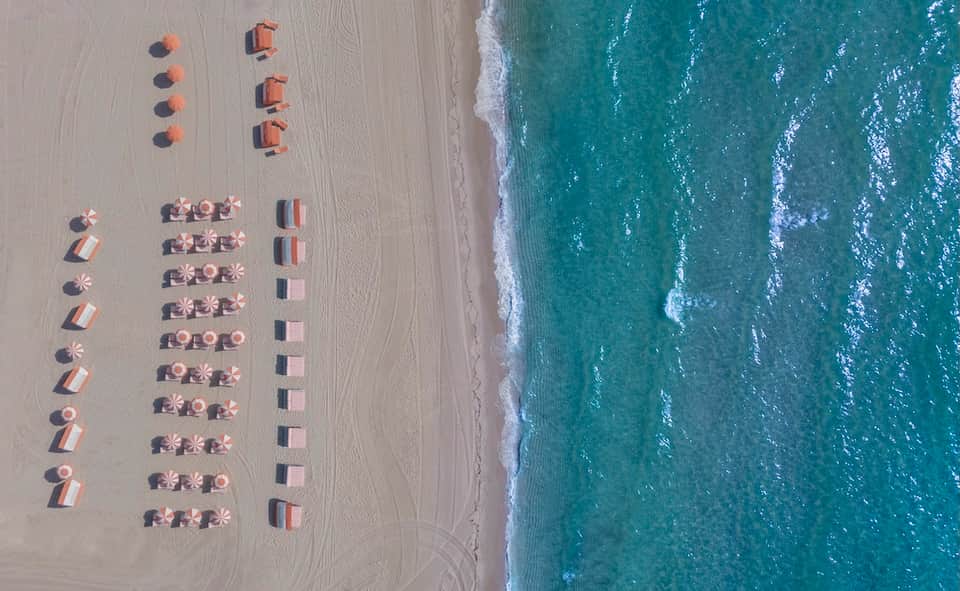 Aerial beach view with organized rows of umbrellas, loungers, and ocean waves