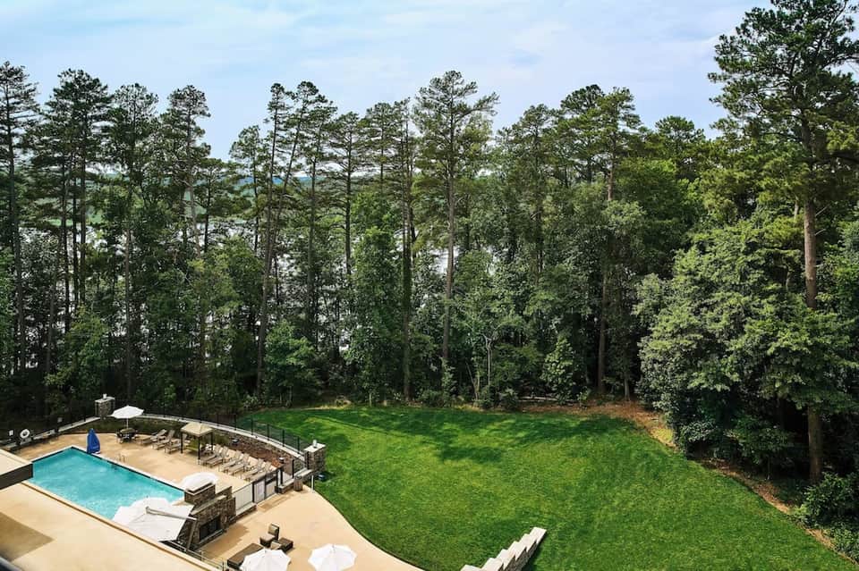 Resort pool surrounded by forest canopy with manicured lawn and stone patio