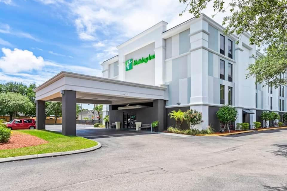 Contemporary white Holiday Inn hotel exterior with covered entrance and landscaping