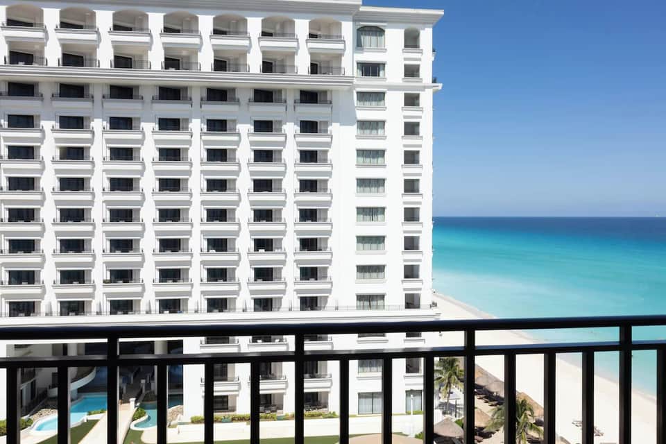 White multi-story beachfront hotel building with ocean and sand beach visible