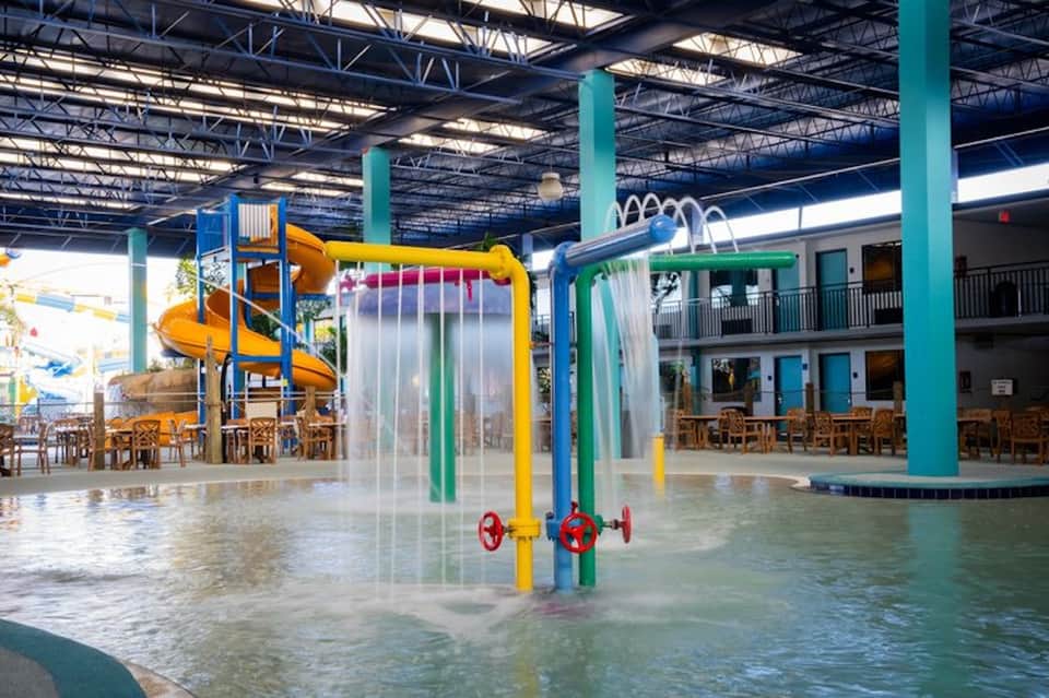 Indoor water park with colorful water slides, splash pad, and supervised play area