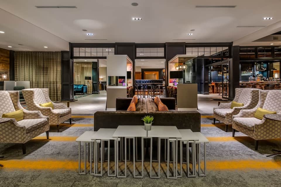 Upscale hotel lobby with patterned chairs, modern furnishings, and open floor plan design