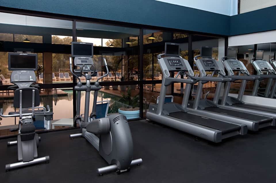 Gym with cardio equipment, treadmills, and floor-to-ceiling windows overlooking nature