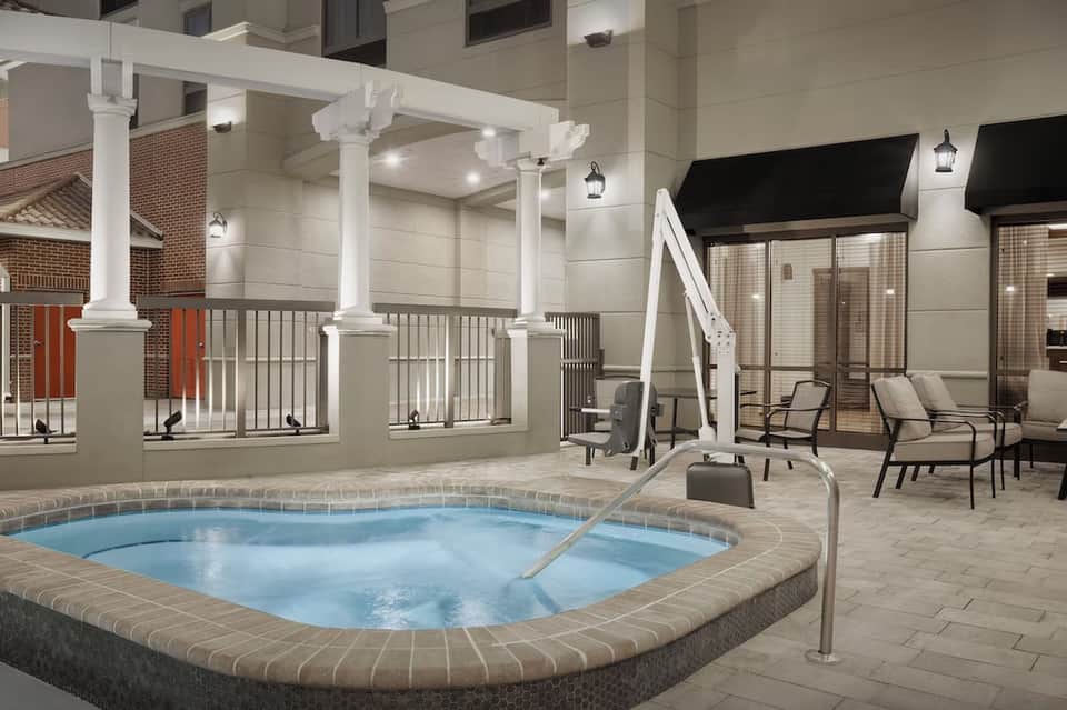 Indoor hot tub with pergola structure, lounge seating, and evening lighting