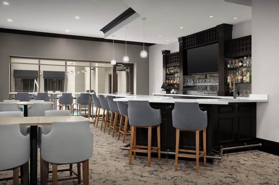Modern bar and lounge area with black cabinetry, white countertop, and mirrored walls