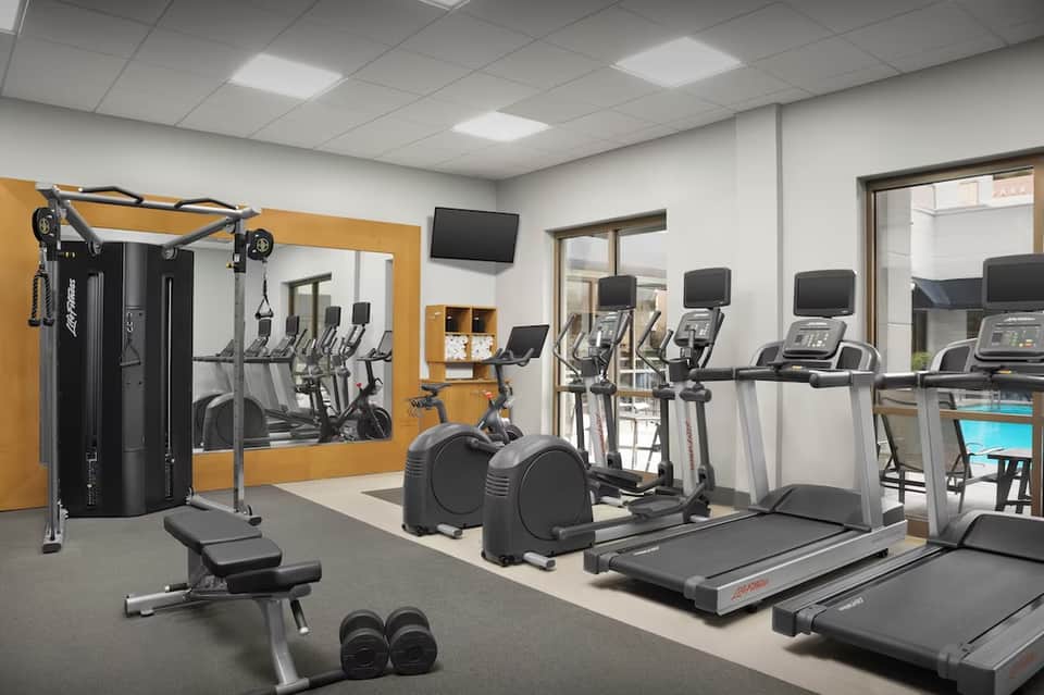 Modern fitness center with treadmills, elliptical machines, weights, and strength training equipment