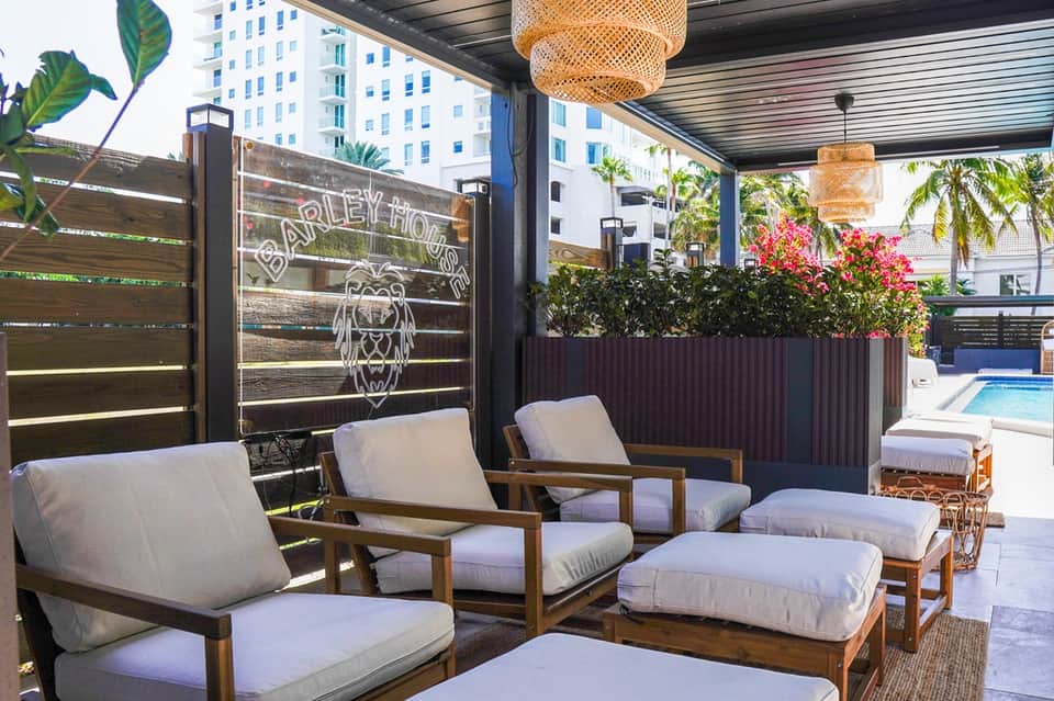 Contemporary outdoor lounge area with wooden seating, woven pendant lights, and pool view