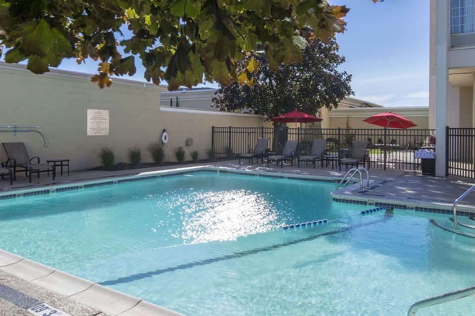 Resort outdoor swimming pool with lounge chairs, umbrellas, and tropical landscaping