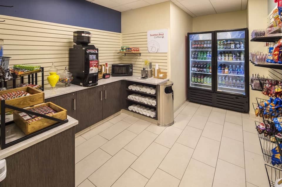 Hotel lobby market area with coffee station, refrigerated beverages, snacks, and hospitality supplies