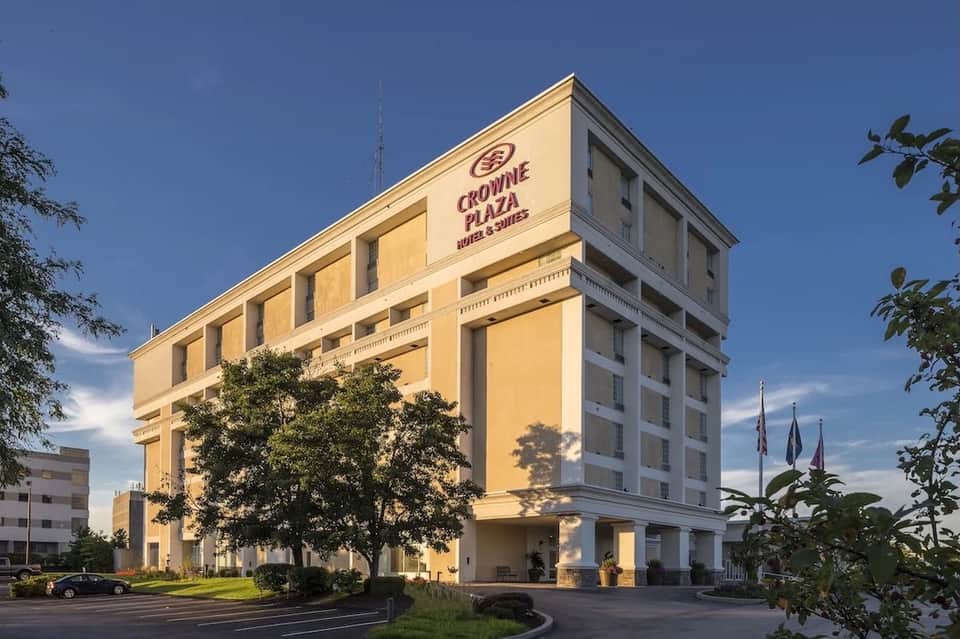 Crowne Plaza hotel building exterior with yellow facade, landscaping, and parking area