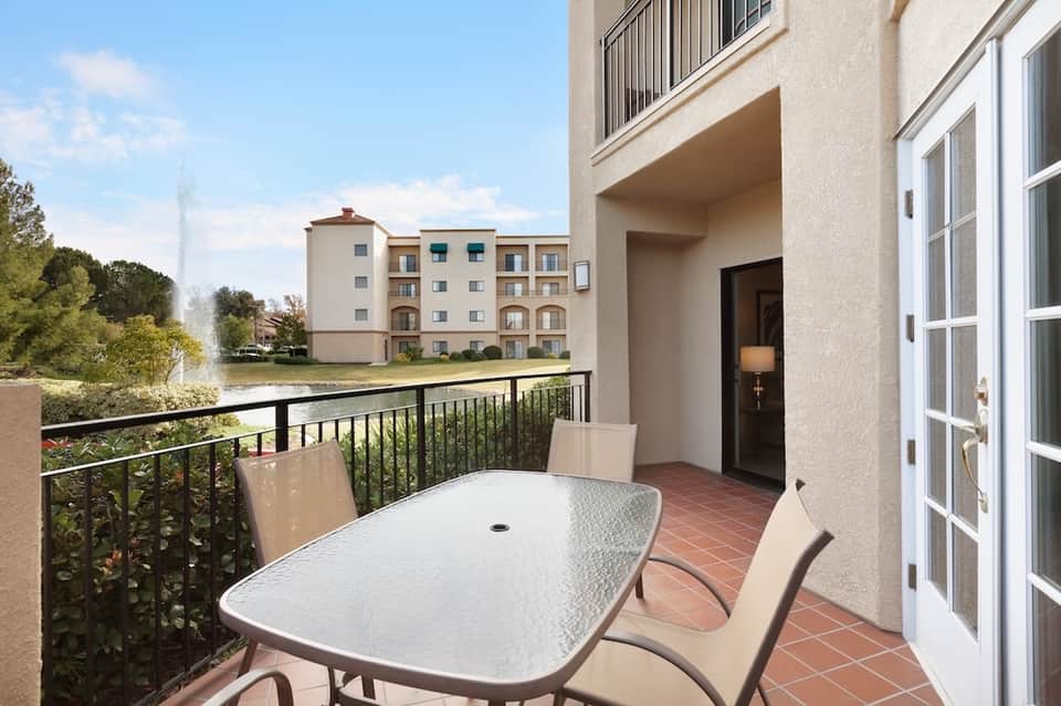 Balcony dining table overlooking calm waterway and distant buildings with clear blue sky