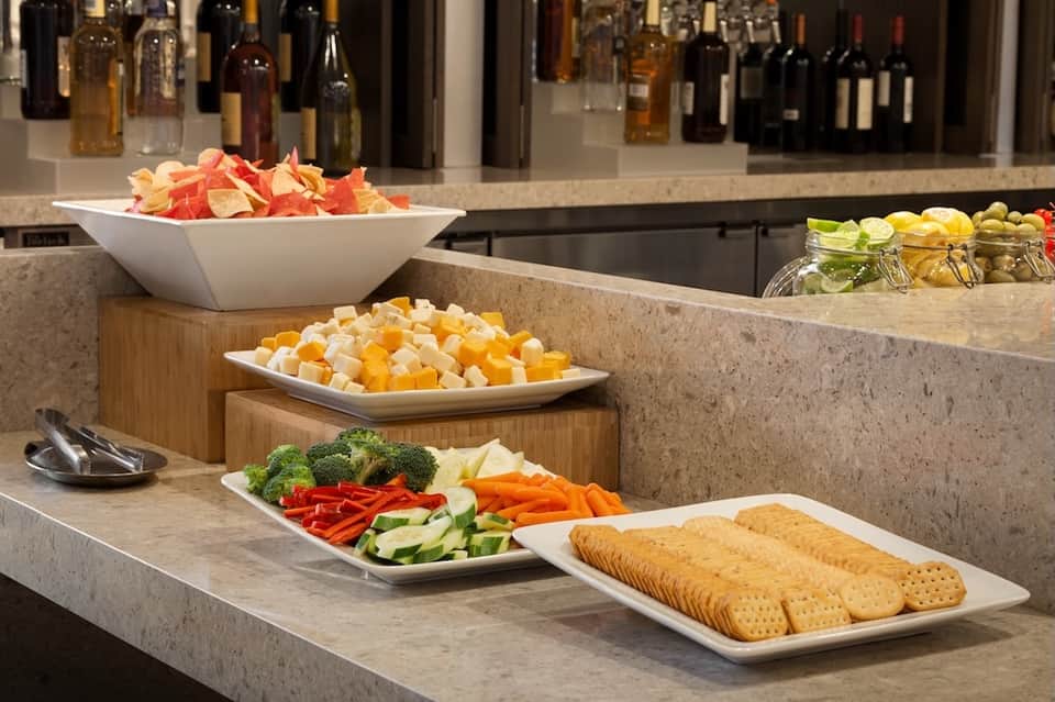 Resort buffet spread displaying fresh vegetables, cheese, crackers, and various appetizers with wine bottles