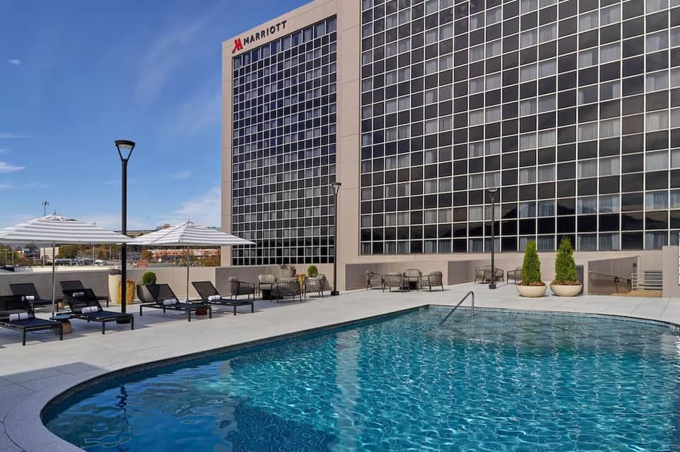 Marriott hotel rooftop pool at sunset with black lounge chairs and city skyline view