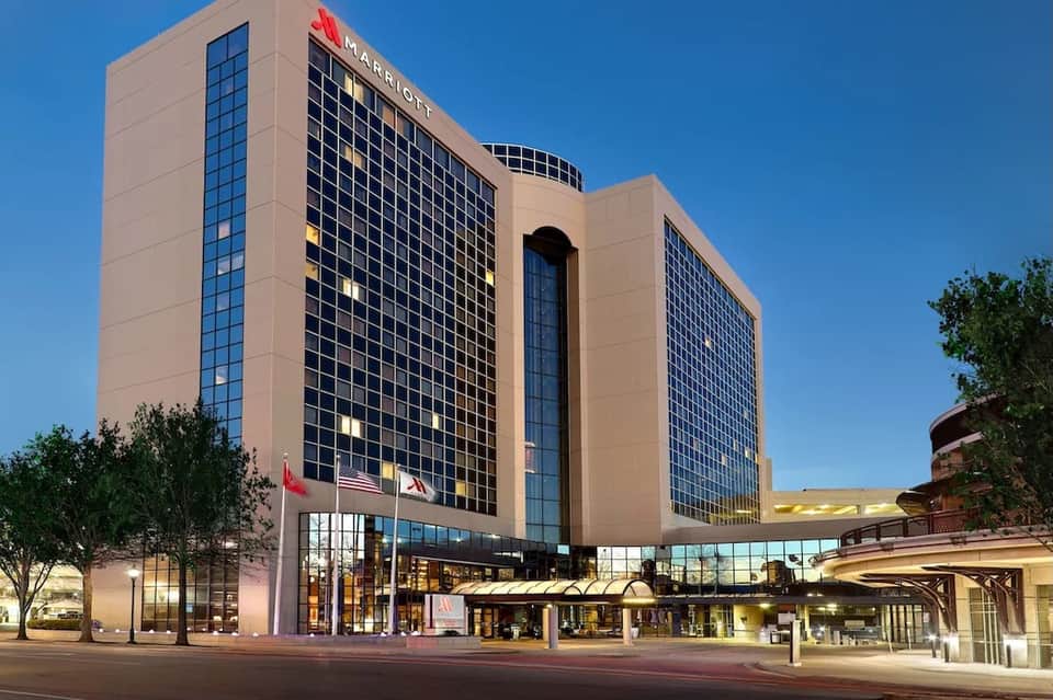 Marriott hotel tower at dusk with illuminated entrance and clear blue sky