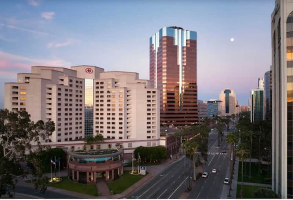 Urban hotel exterior at dusk with lit towers and city skyline