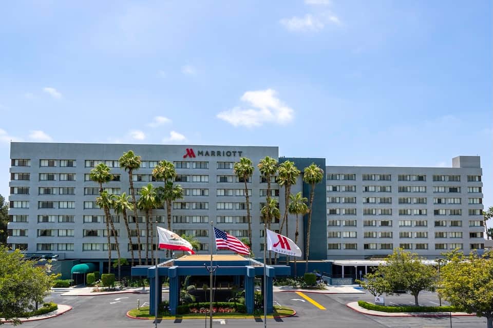 Modern Marriott hotel exterior with palm trees, flags, and contemporary architecture