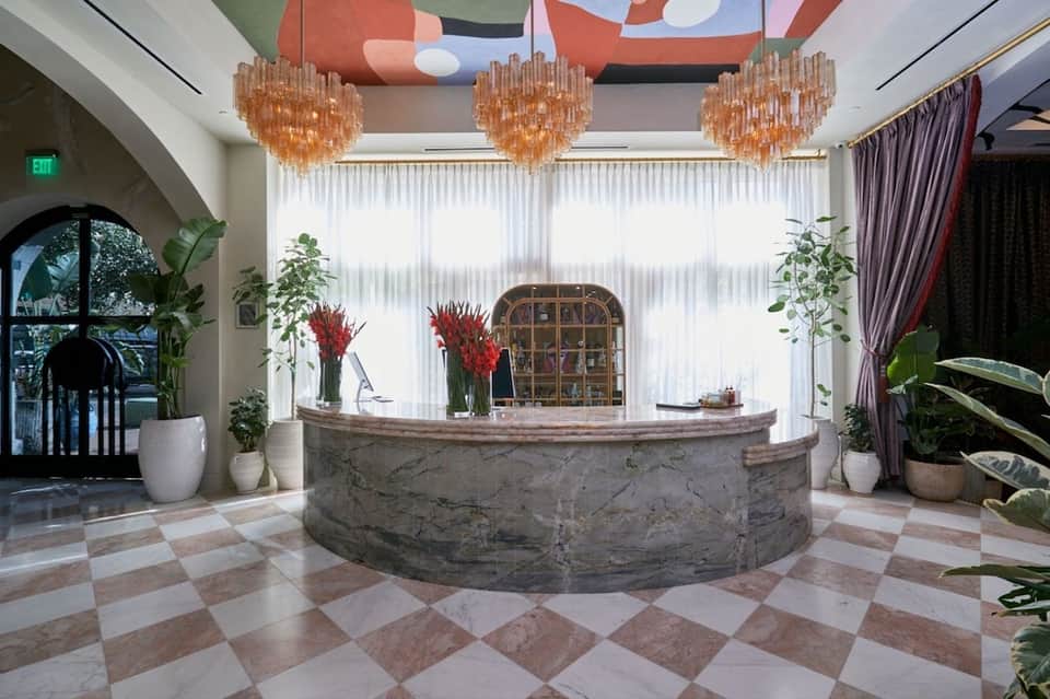 Elegant hotel lobby with marble reception desk, chandeliers, and decorative plants