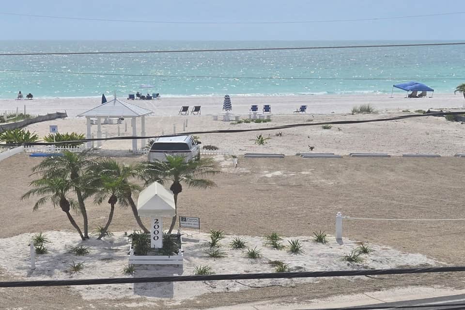 Beach access with pavilion, lounge chairs, turquoise ocean water, and white sand from elevated viewpoint