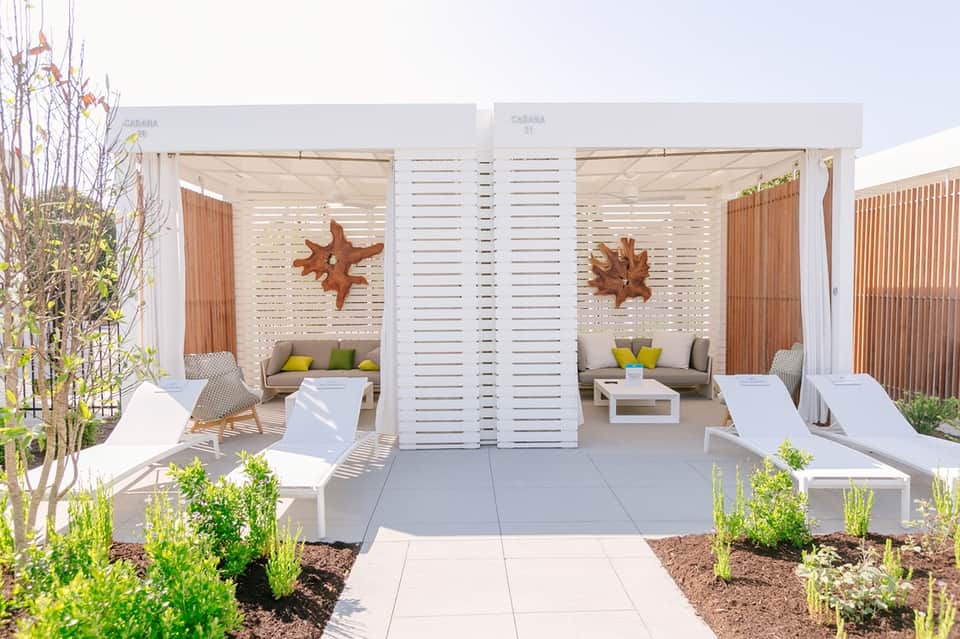 Luxury cabana with white louvered doors, seating areas, and decorative starfish accents