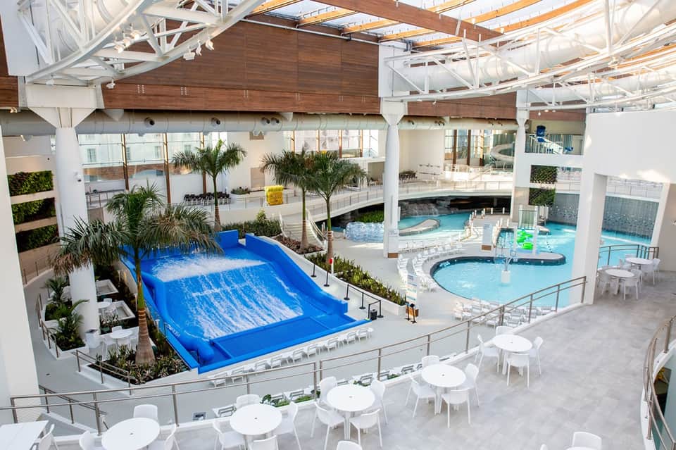 Indoor water park with blue wave slide and multiple pools under white ceiling