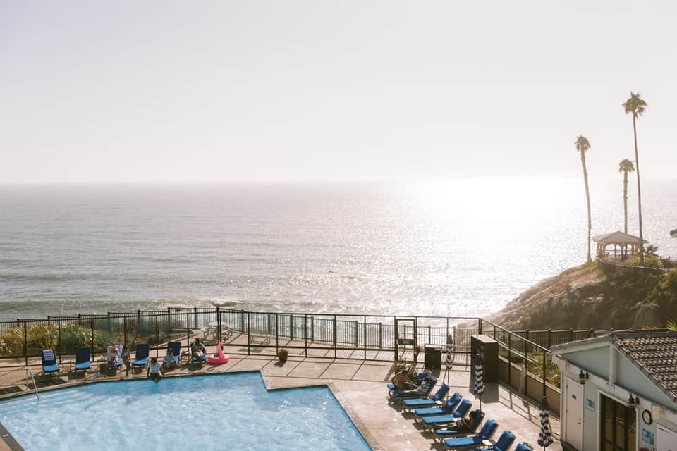 Coastal resort pool overlooking the Pacific Ocean with palm trees and cliffside gazebo