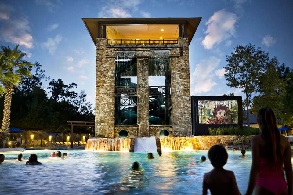 Stone tower with waterfall feature in resort pool surrounded by guests