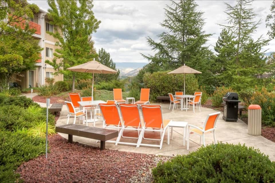 Outdoor lounge area with orange sling chairs, umbrellas, and mountain valley views