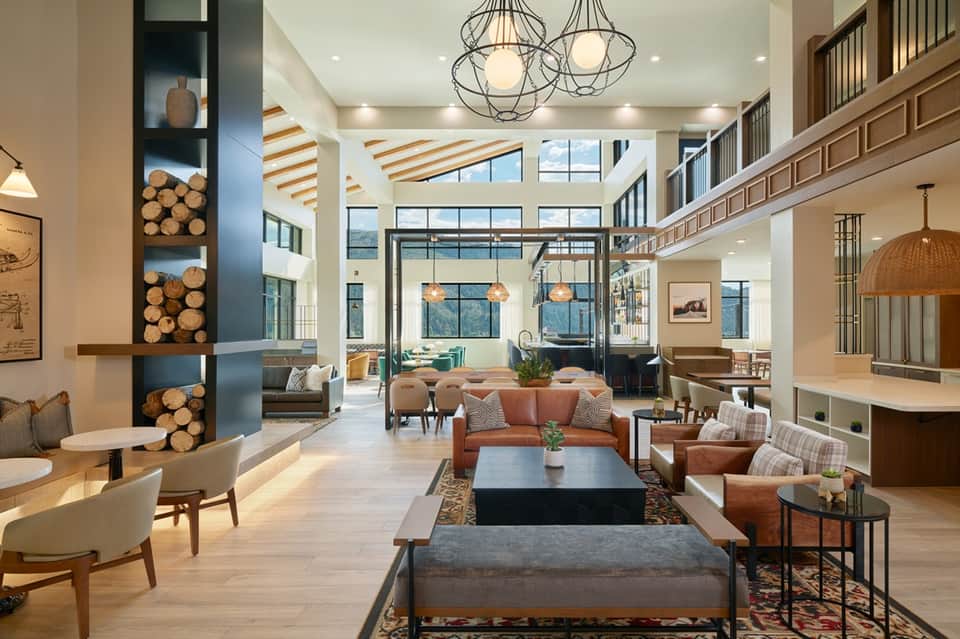 Modern hotel lobby with high ceilings, wooden beams, fireplace, and contemporary furniture