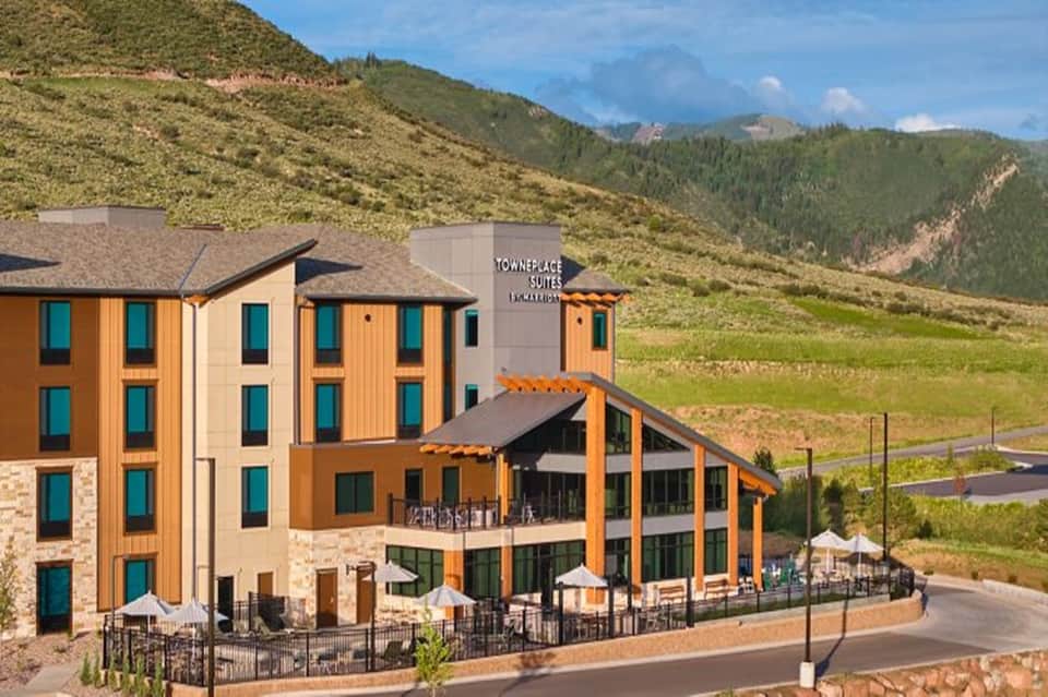 Mountain resort with orange and tan exterior, large windows, terraces, and scenic valley backdrop