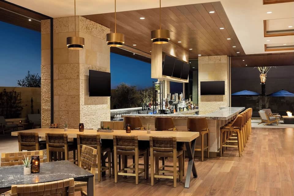 High-end rooftop lounge with bar seating, pendant lighting, and city views