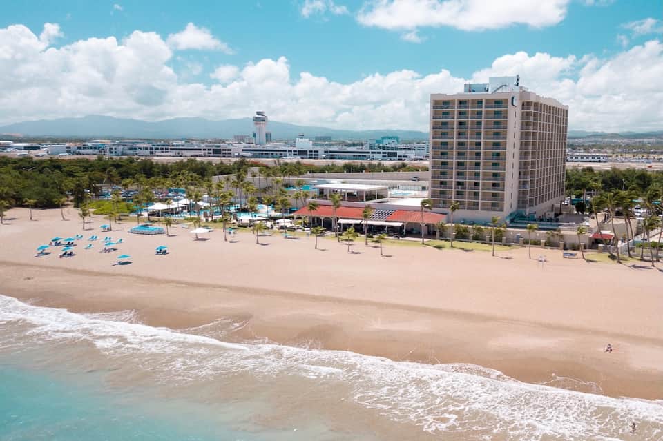 Beachfront resort with sandy beach, palm trees, and high-rise hotel building