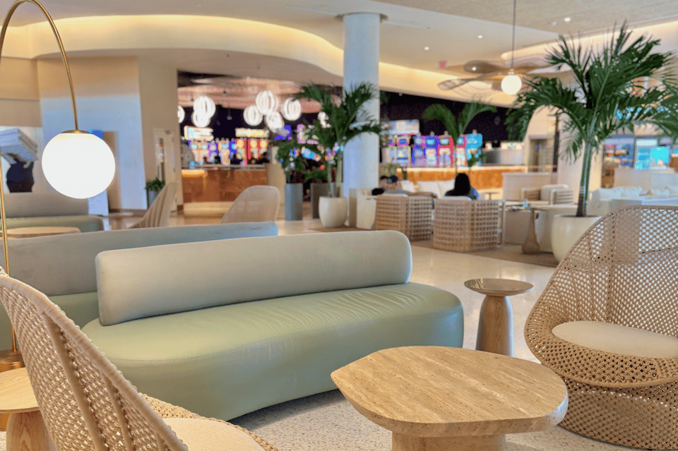 Modern hotel lobby lounge with curved sofa, pendant lighting, potted plants, and contemporary furnishings