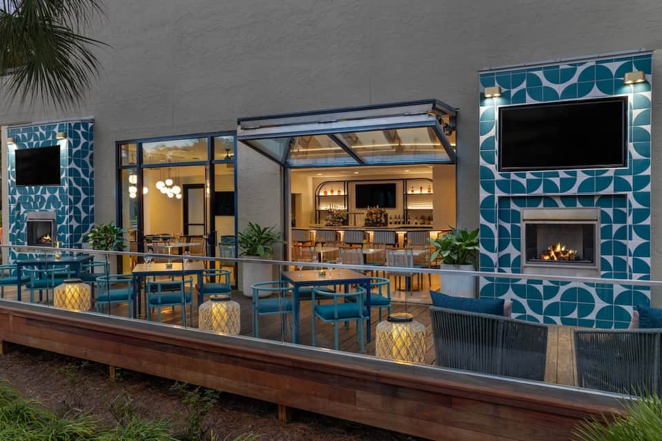 Modern outdoor bar and lounge area with blue patterned tile walls, fireplace, and contemporary seating