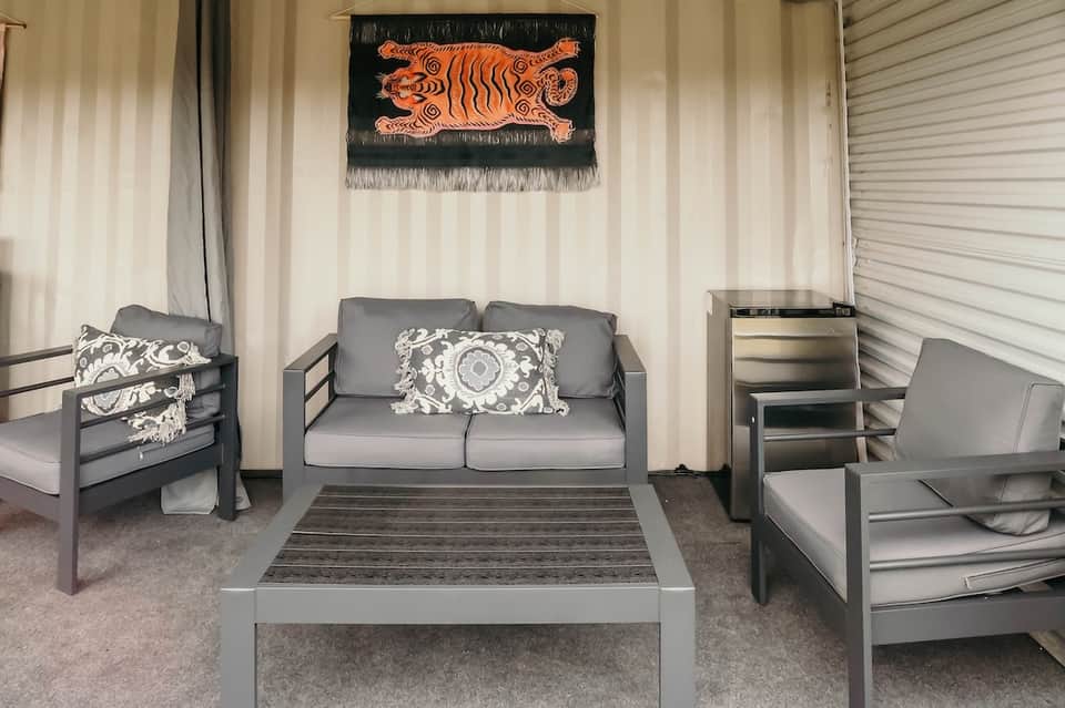 Contemporary patio lounge area with gray furniture, decorative pillows, and tribal wall art