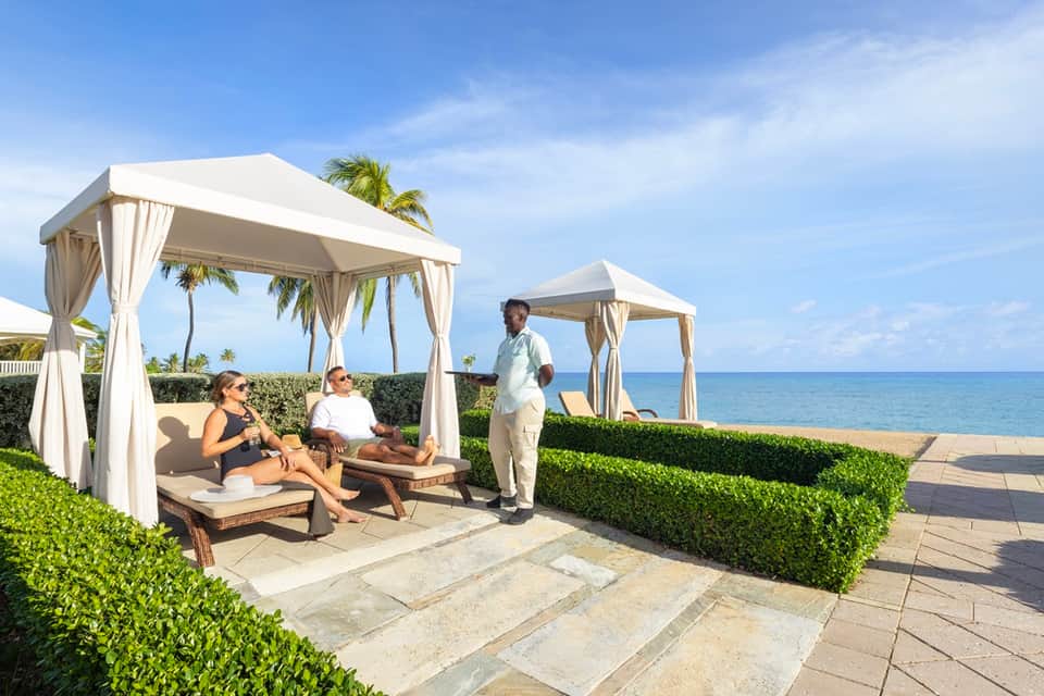 Beachfront cabanas with white curtains and ocean view service