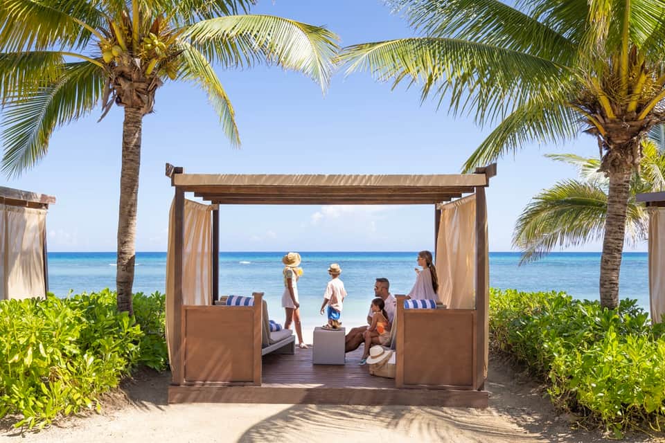 Beachfront cabana with wooden pergola, ocean view, and family gathering area
