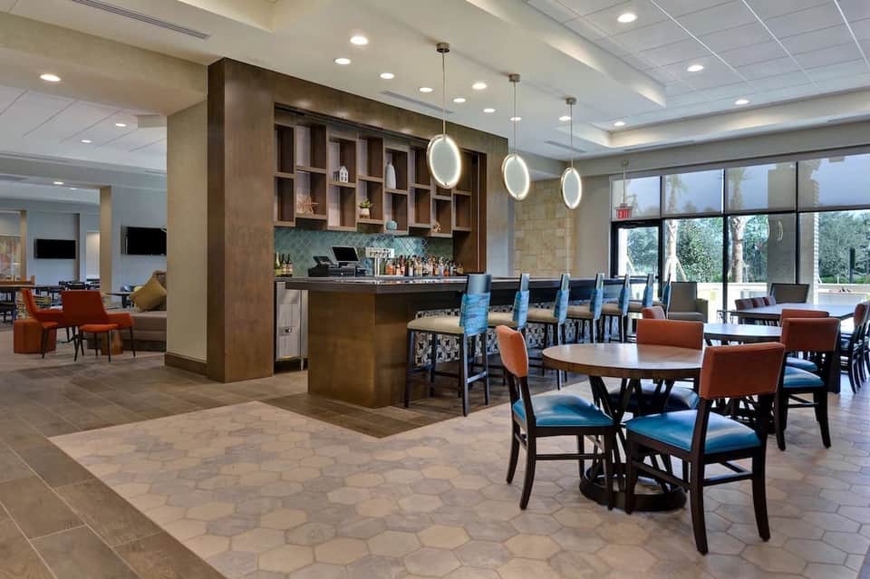 Modern resort lobby lounge with bar, wood accents, blue chairs, and fireplace