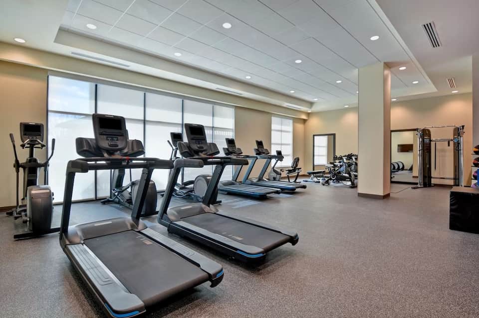 Hotel fitness center with treadmills and exercise equipment by large windows