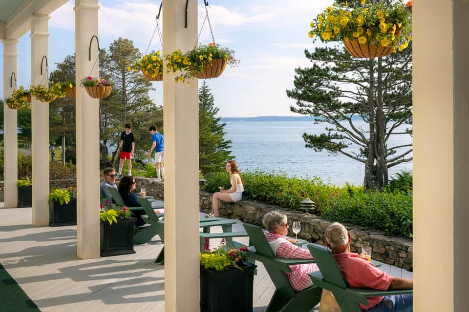 Waterfront pergola with hanging baskets, Adirondack chairs, and ocean views with columns
