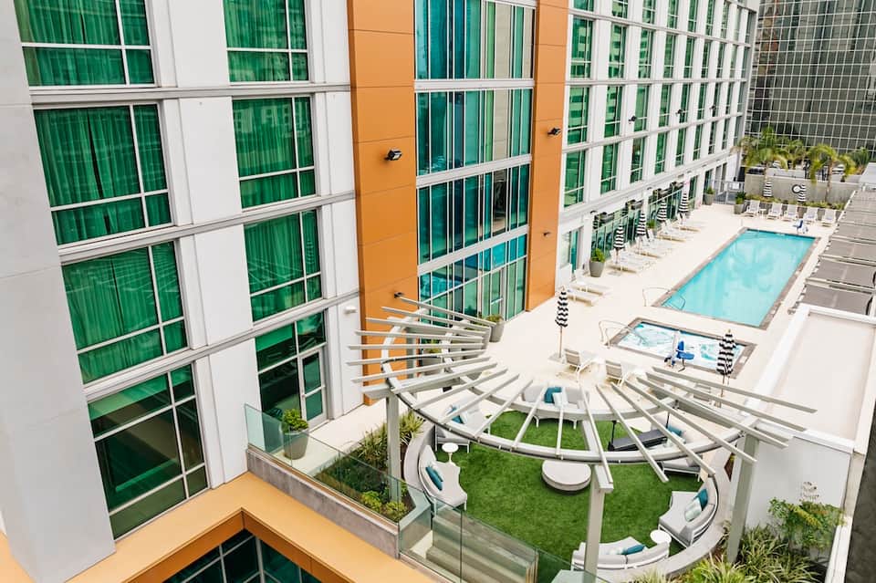 Rooftop pool and lounge area between residential towers with modern white furniture