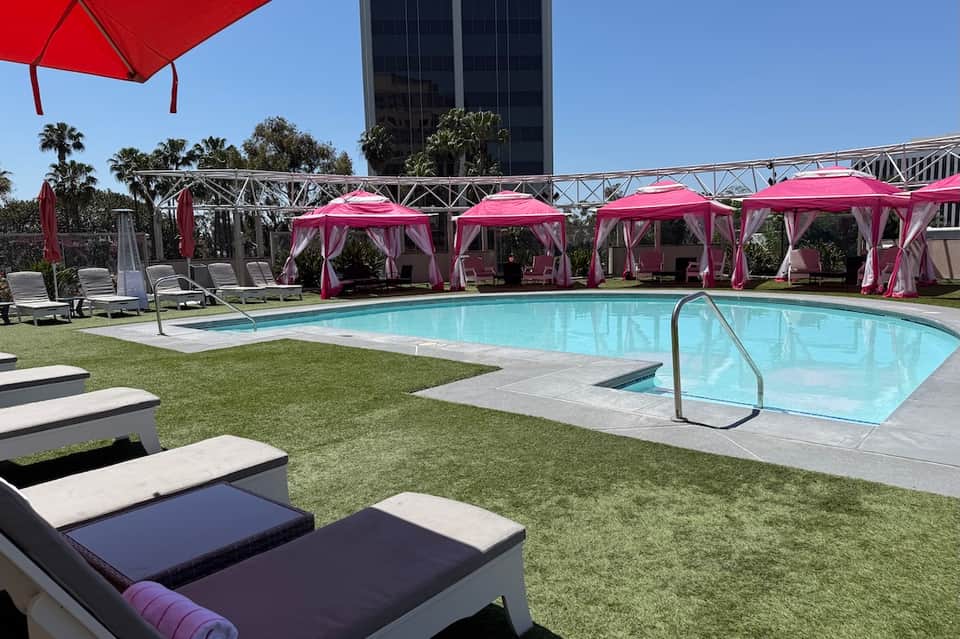 Resort pool with pink cabanas, umbrellas, and manicured lawn