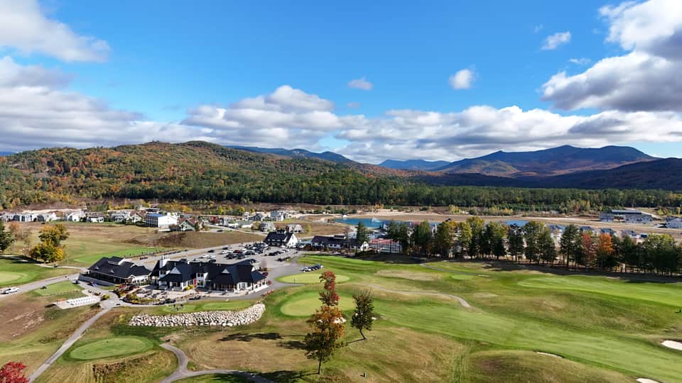 Aerial view of golf course clubhouse with mountain landscape in background