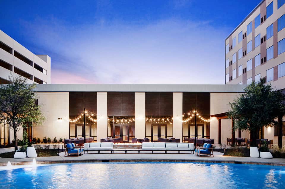 Modern hotel courtyard with pool, lounge seating, and minimalist architecture at dusk