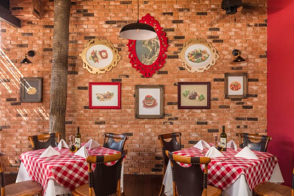 Casual Italian restaurant interior with exposed brick wall and red gingham tablecloths