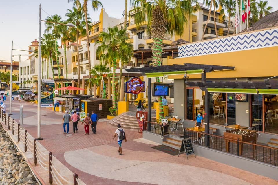 Beachfront plaza with yellow buildings, palm trees and casual dining area