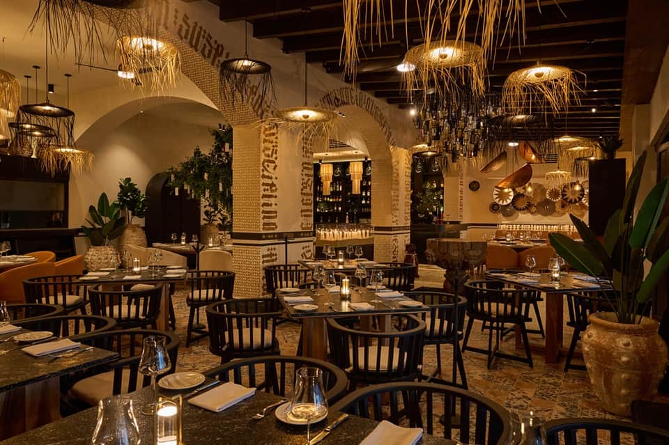Contemporary restaurant dining room with arched brick columns, hanging light fixtures, and elegant table settings