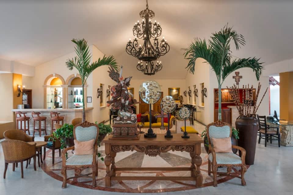 Elegant lobby with ornate chandelier, decorative sculptures, bar area, and classical furnishings