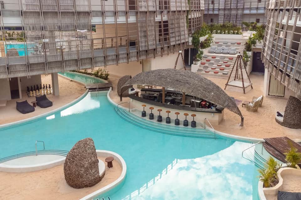 Modern resort pool complex with curved turquoise pools and tiki bars