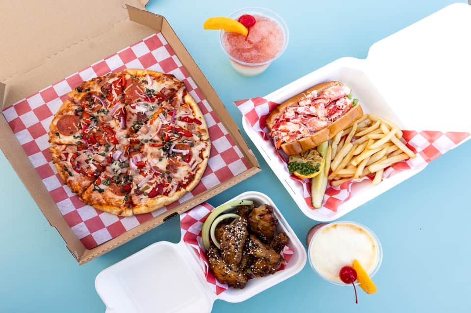 Casual dining spread featuring pizza, lobster sandwich, fries, appetizers, and cocktails