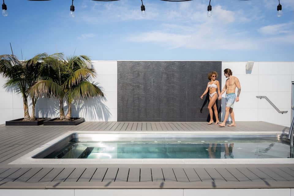 Modern residential pool deck with lounge chairs, palm tree planting, white walls, and minimalist design